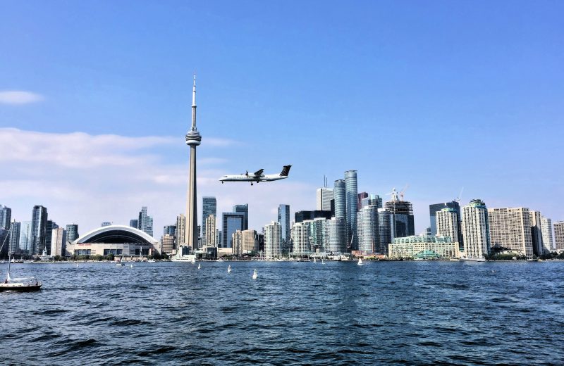 Plane flying over downtown Toronto skyline. Managing airport noise in urban areas is essential for residential development.